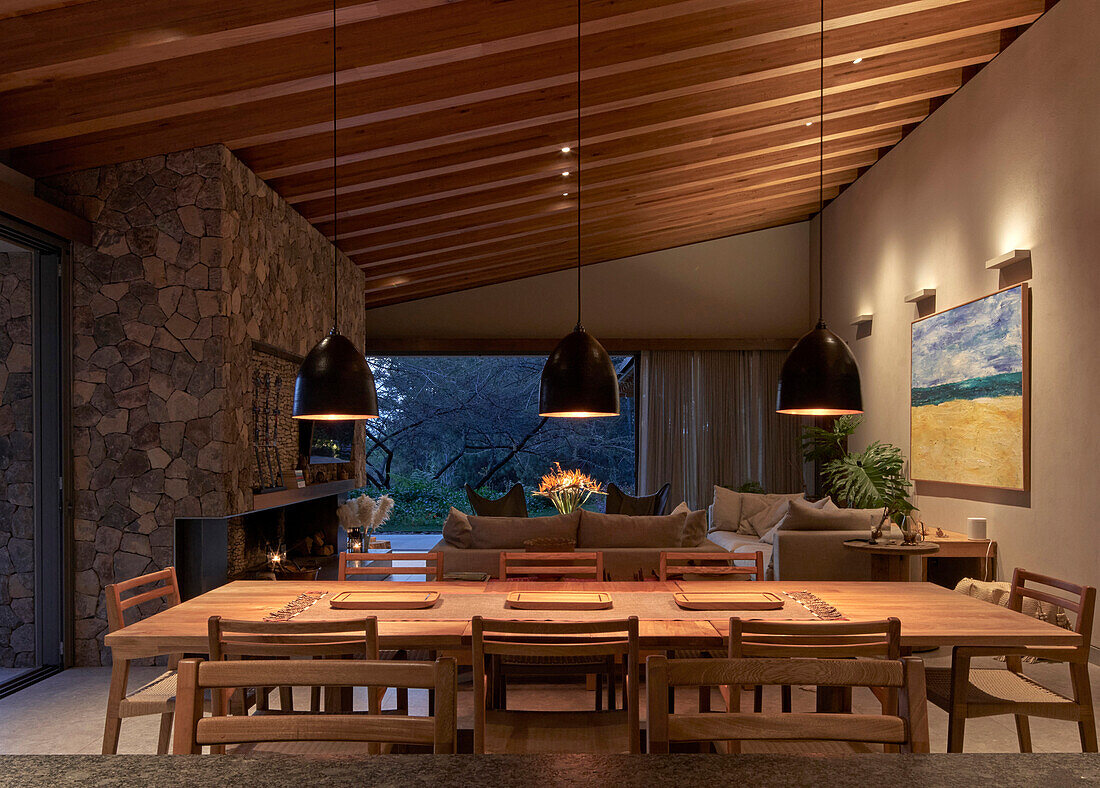 Dining area, hanging lamps above in open living room at dusk