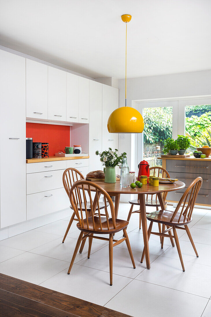 Bright kitchen with dining area and yellow pendant light, view of the garden