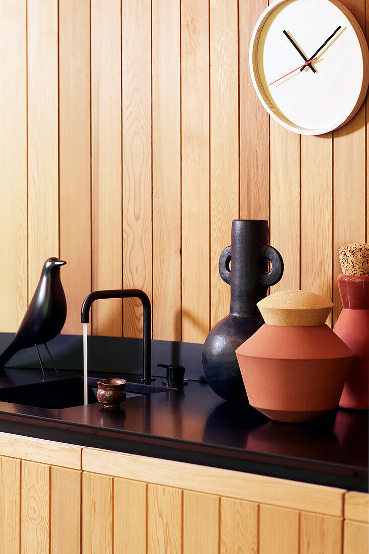 Kitchen unit with wood paneling, black countertop and decorative objects