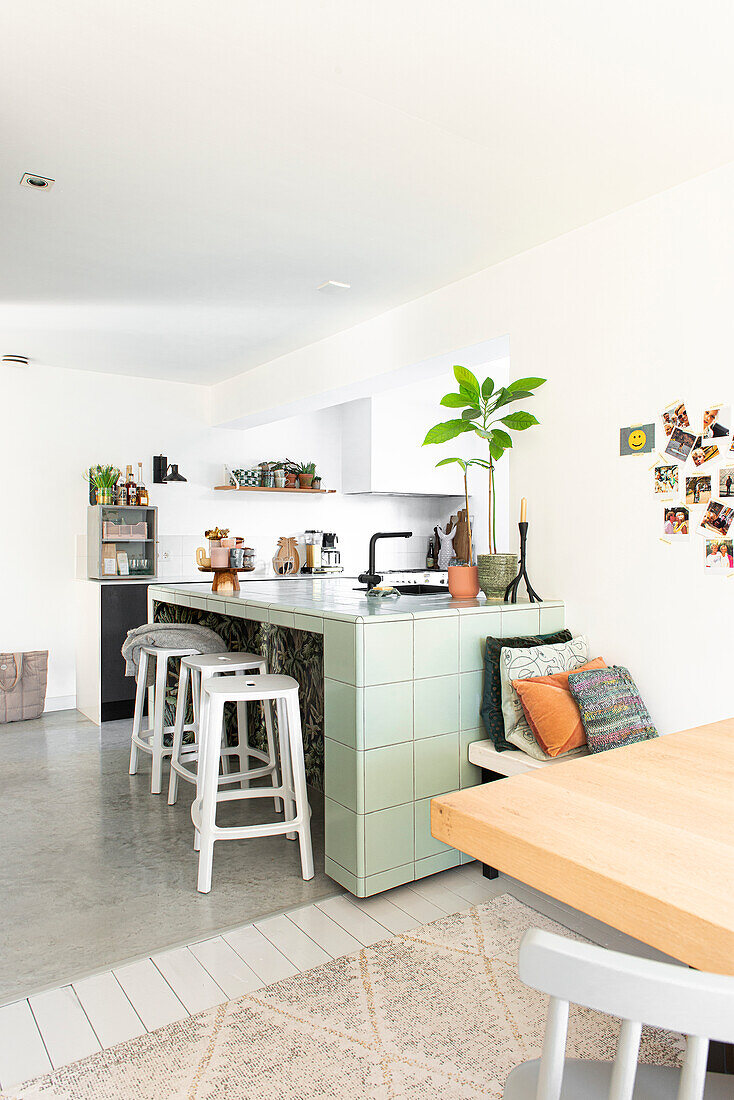 Modern kitchen with mint green tiled island with dining area in the foreground