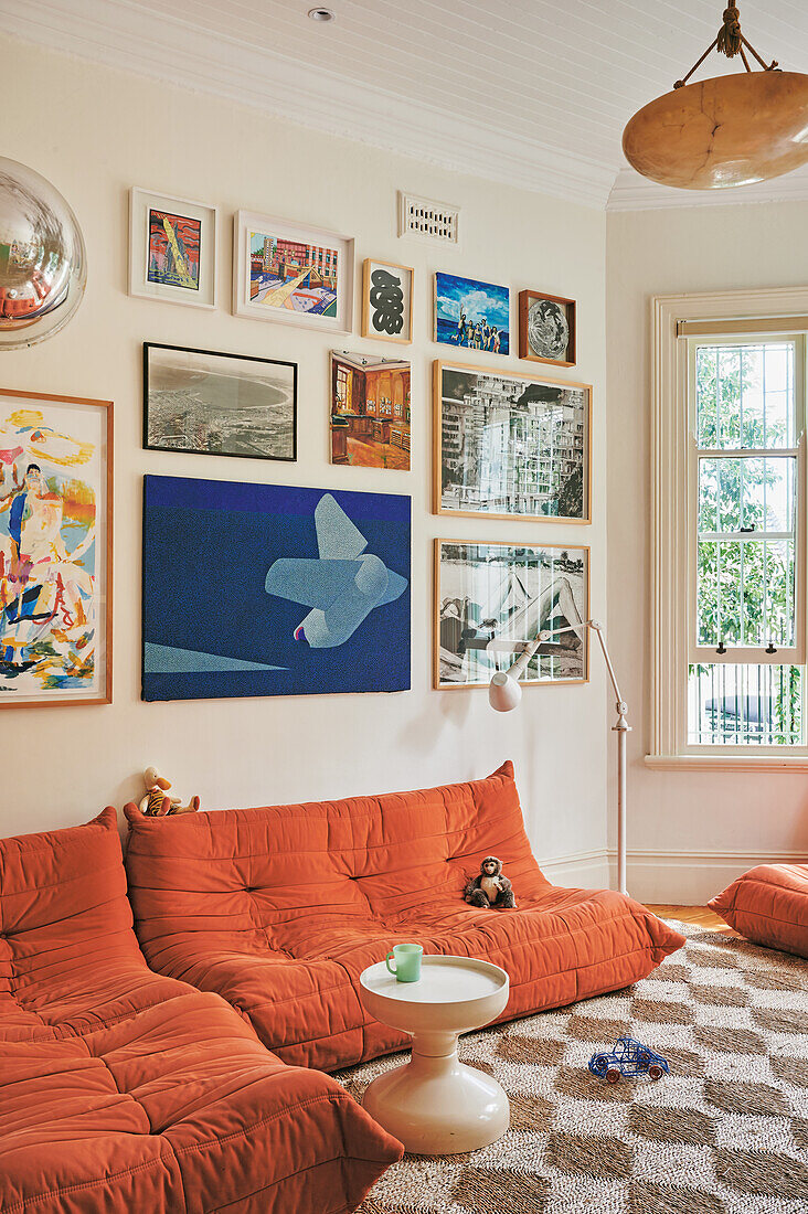 Wohnzimmer mit orangefarbenem Sofa und Bilderwand