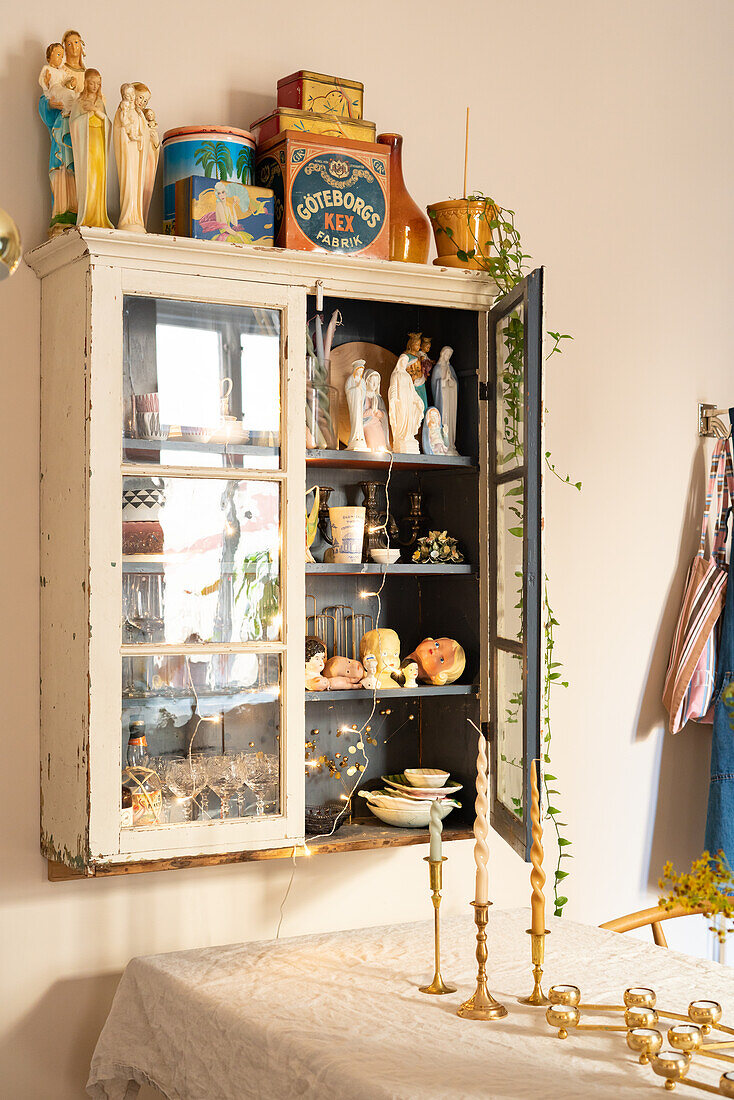 Vintage display cabinet with collector's items and candlesticks on the table