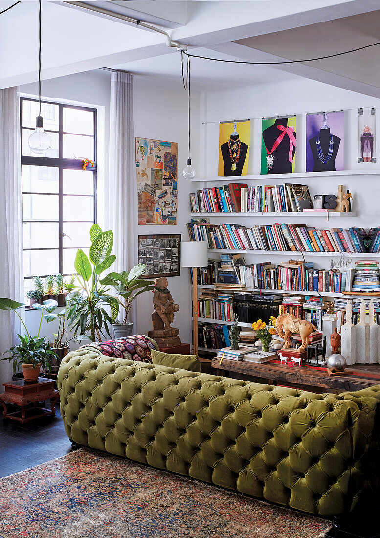 View of green velvet sofa and wall of books in loft living room