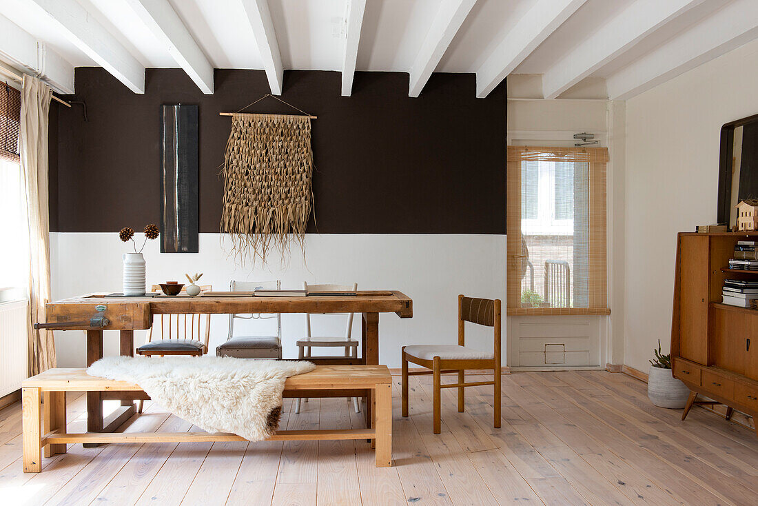 Wooden table with bench and chairs in dining room with retro furniture