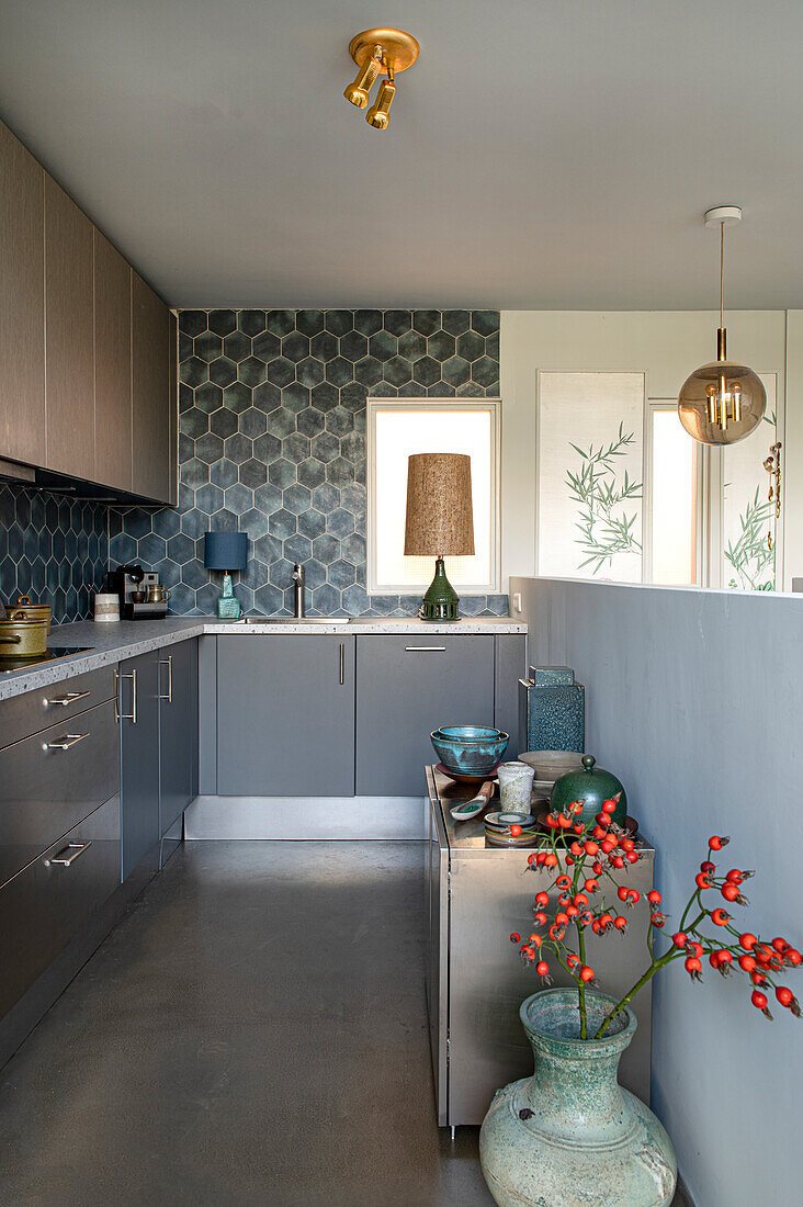 Narrow kitchen with grey cupboard fronts and matching wall tiles