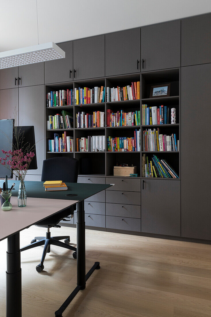 Modern study with large, dark bookshelf