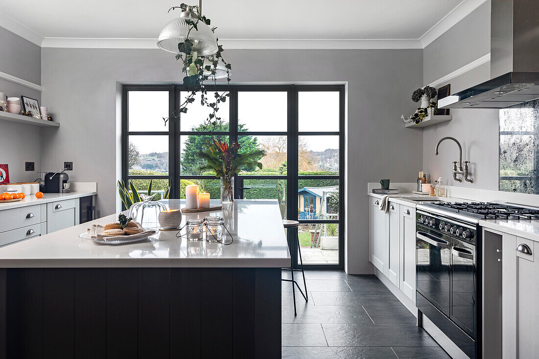 Modern kitchen with black kitchen island, grey walls and view of the garden