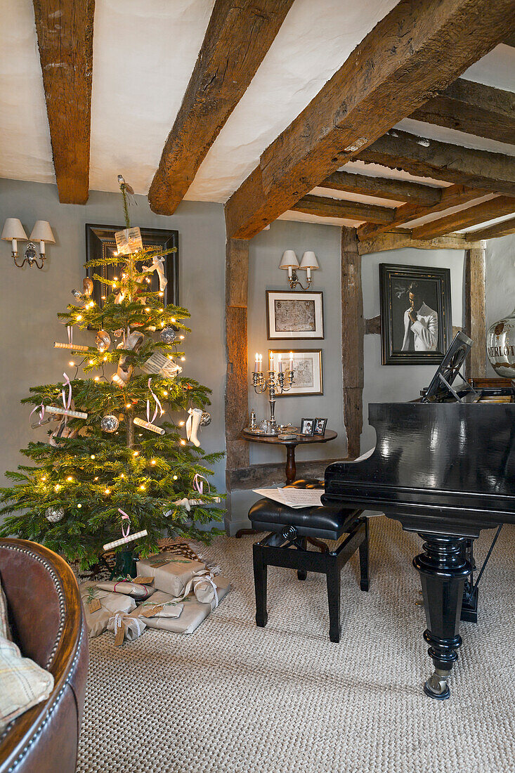 Weihnachtlich geschmückter Raum mit Holzbalkendecke, einem Flügel und Tannenbaum