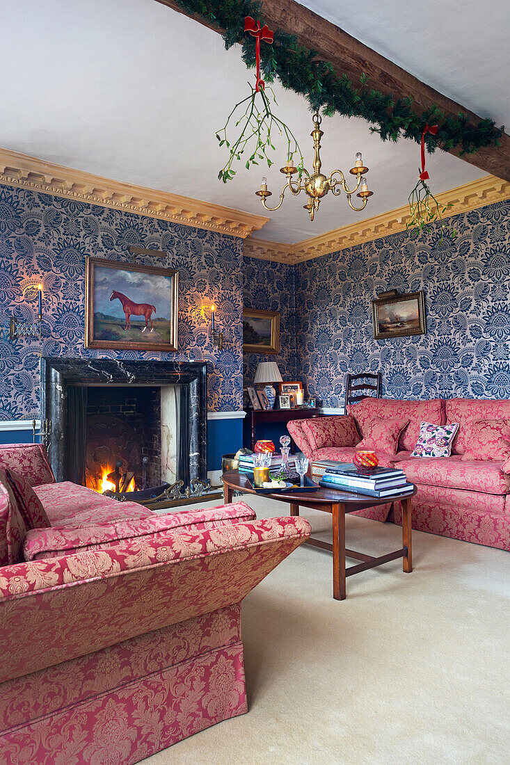 Living room with fireplace, patterned wallpaper and red upholstered furniture