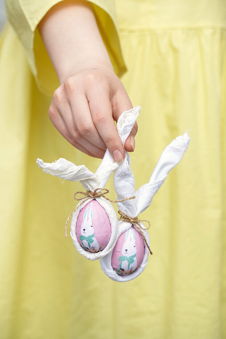 Hand holding homemade Easter decoration with painted eggs