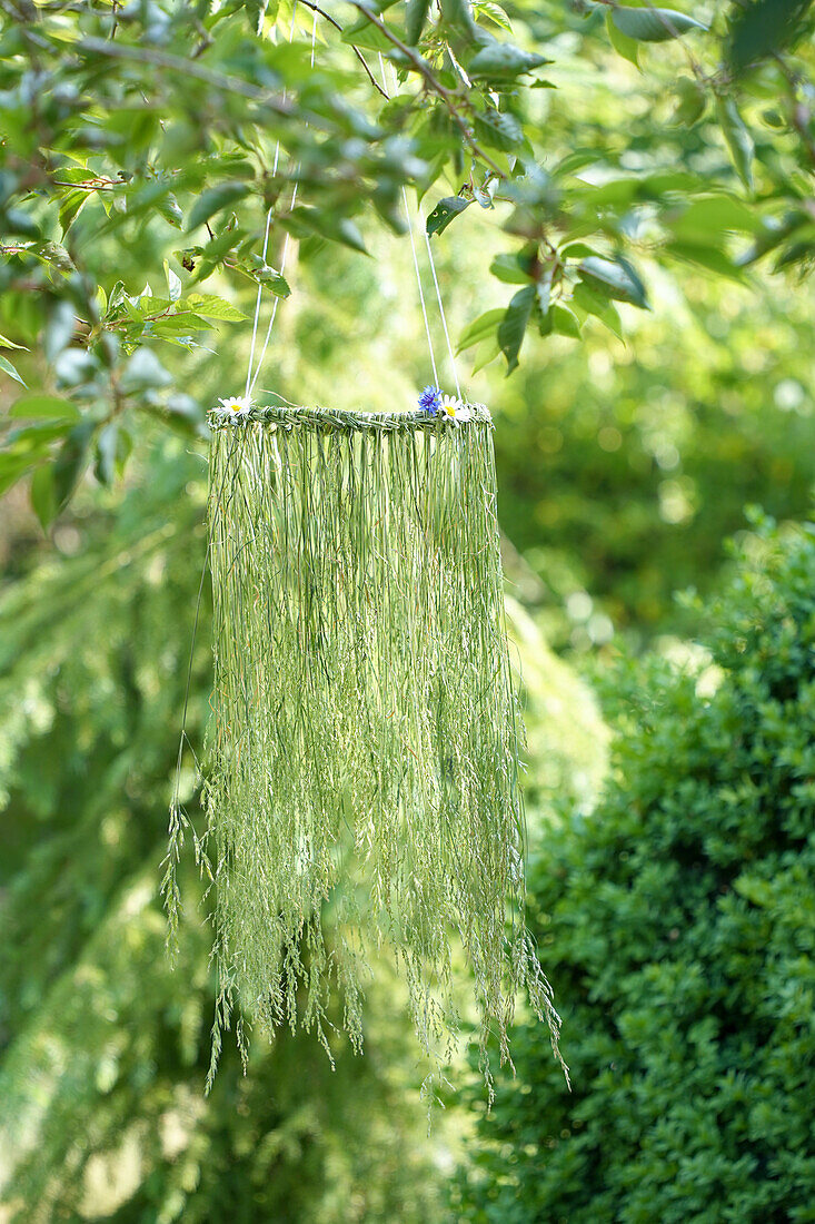 Homemade hanging decoration made from woven grasses and flowers in the garden