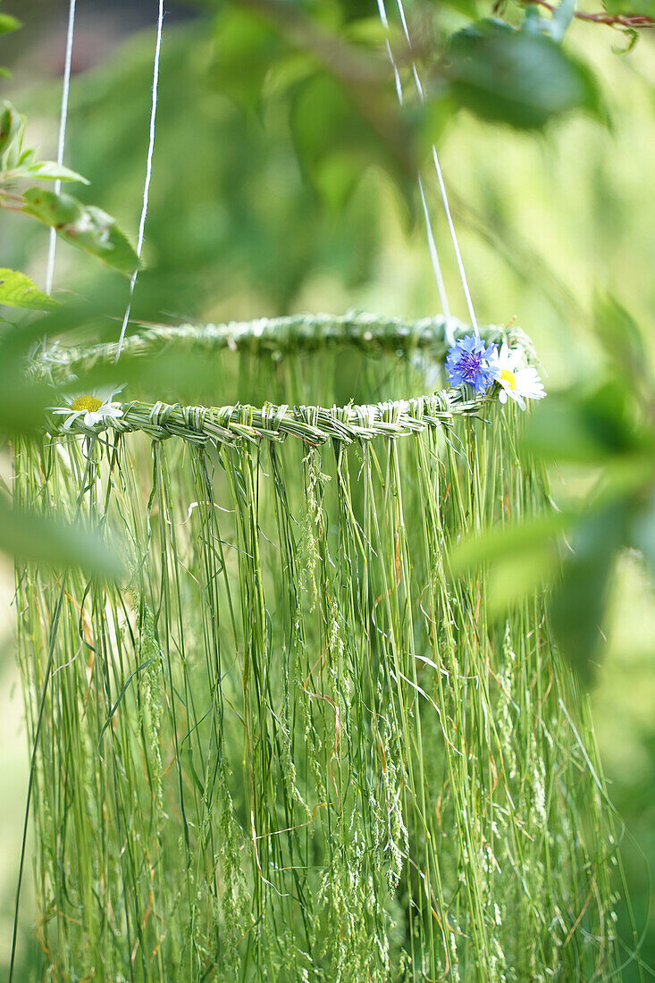 Hanging DIY garden decoration made from woven grasses and wildflowers