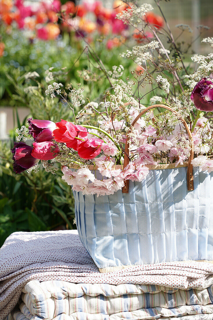 Flower arrangement in a basket on a blanket and cushions outside