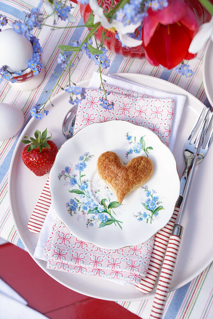 Spring table setting with heart-shaped biscuit and strawberry