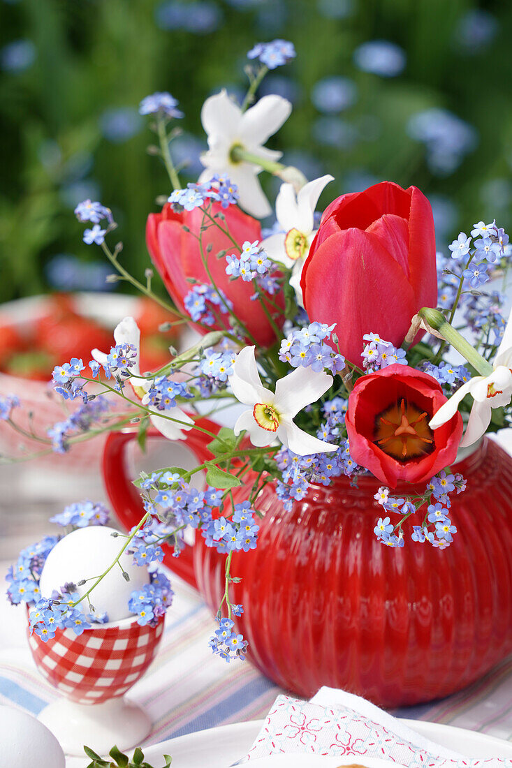 Easter decoration with red tulips (Tulipa) and forget-me-nots in a red teapot