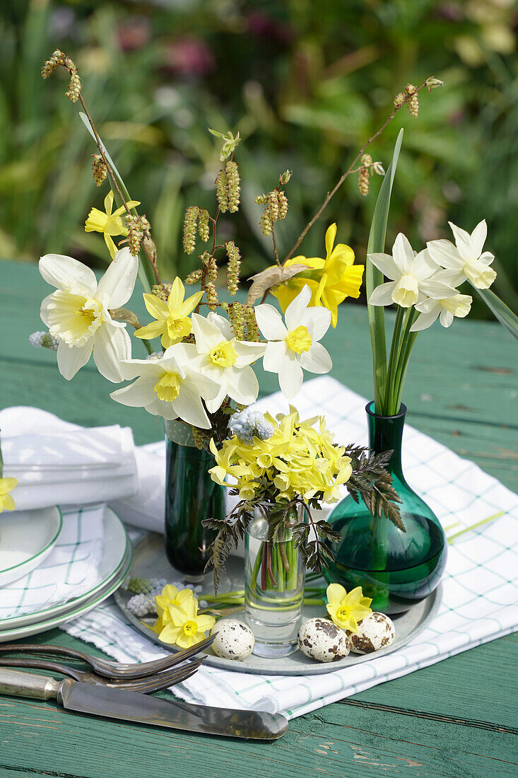 Easter arrangement with daffodils (Narcissus) and meadow grasses on a wooden garden table