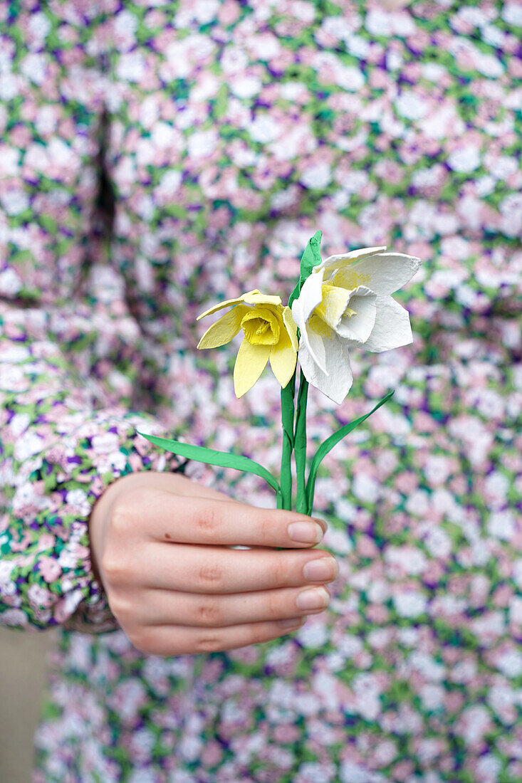 Hand holding DIY paper daffodils in front of patterned dress