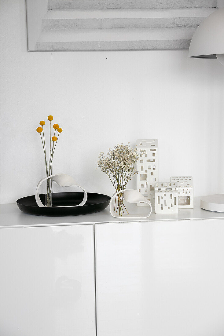 Decorative vases and tea lights on a white sideboard