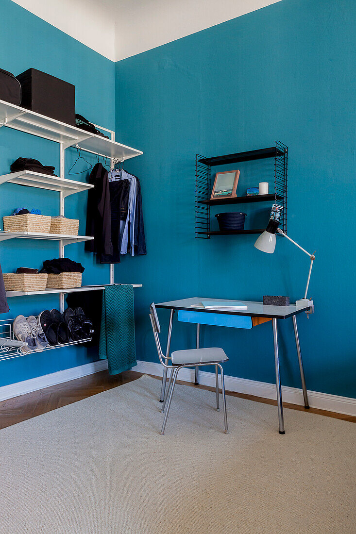 Vintage writing desk and open wardrobe in room with blue walls