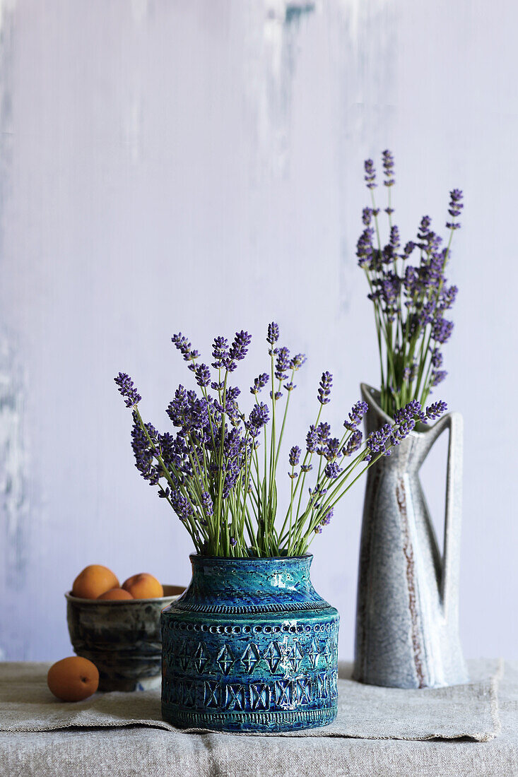 Lavender in two vintage ceramic vases, next to a bowl of apricots