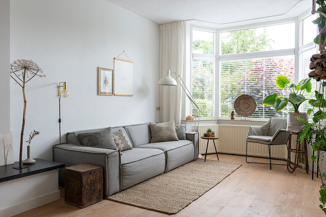 Brightly furnished living room with grey sofa and large bay windows