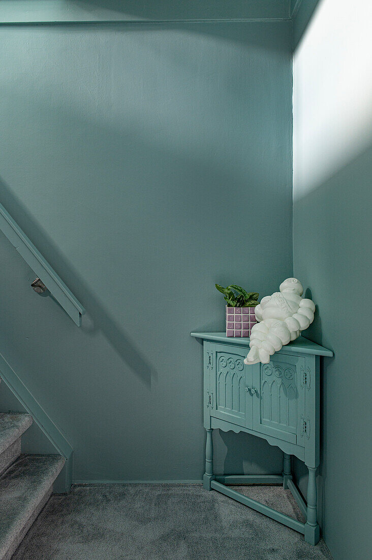 Mint-coloured console table with decorative elements in the staircase