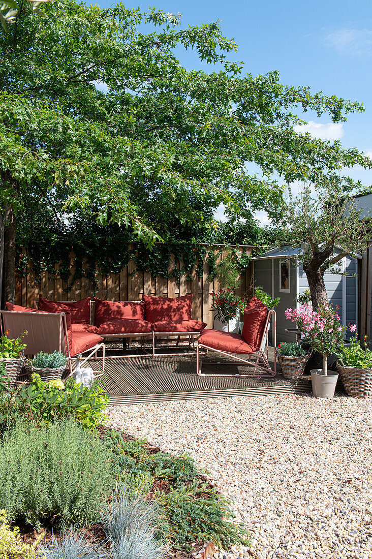 Terrace with red lounge furniture and potted plants in the summer garden