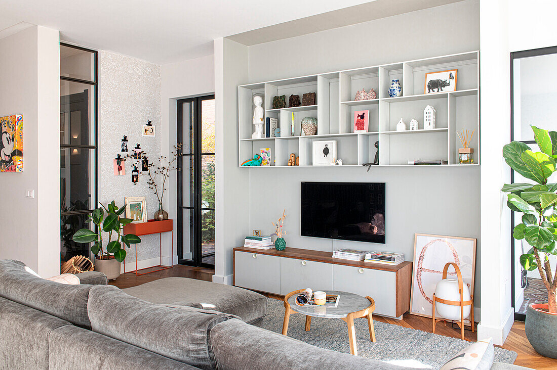 Bright living room with open shelving wall, discreet decoration and house plants