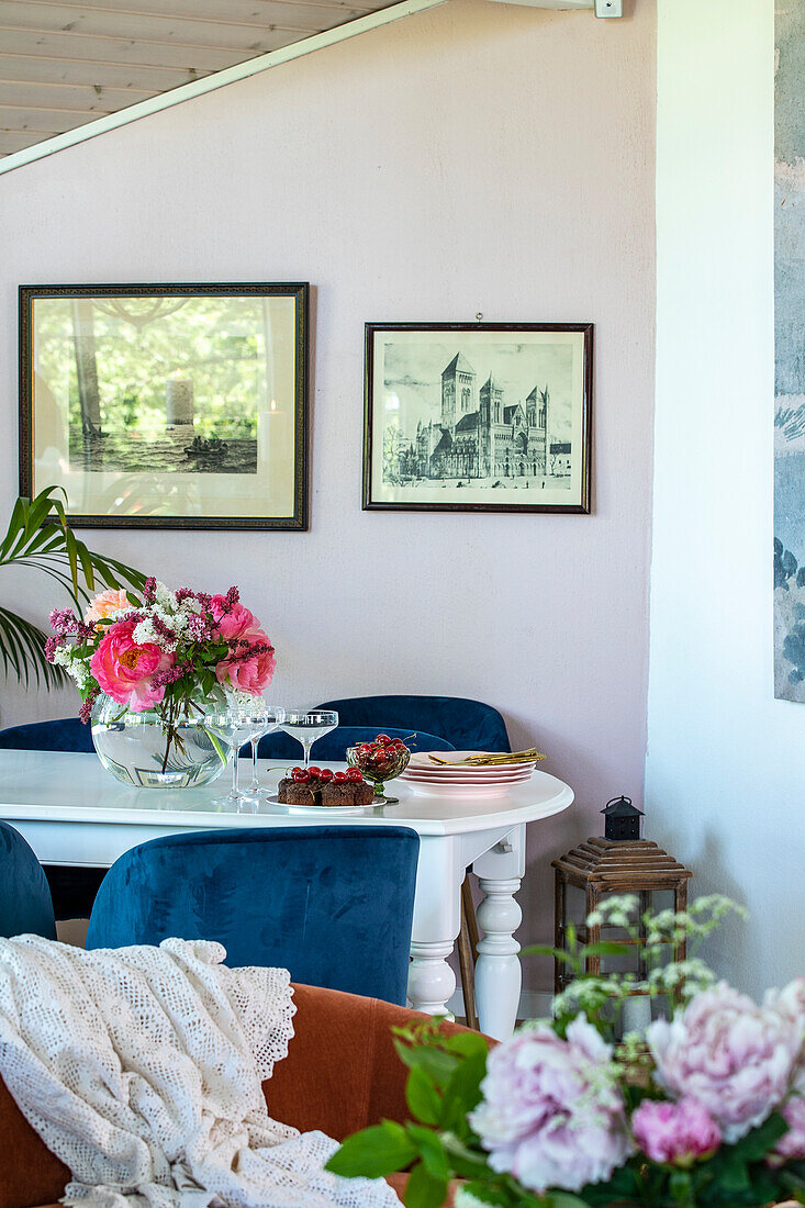 Essbereich mit blauen Samtstühlen und Blumenstrauß auf weißem Tisch