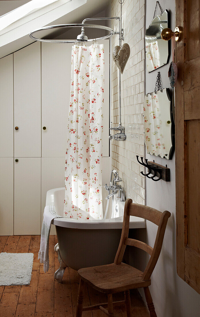 Floral shower curtain and vintage mirrors with chair in tiled bathroom of Brighton home East Sussex, England, UK