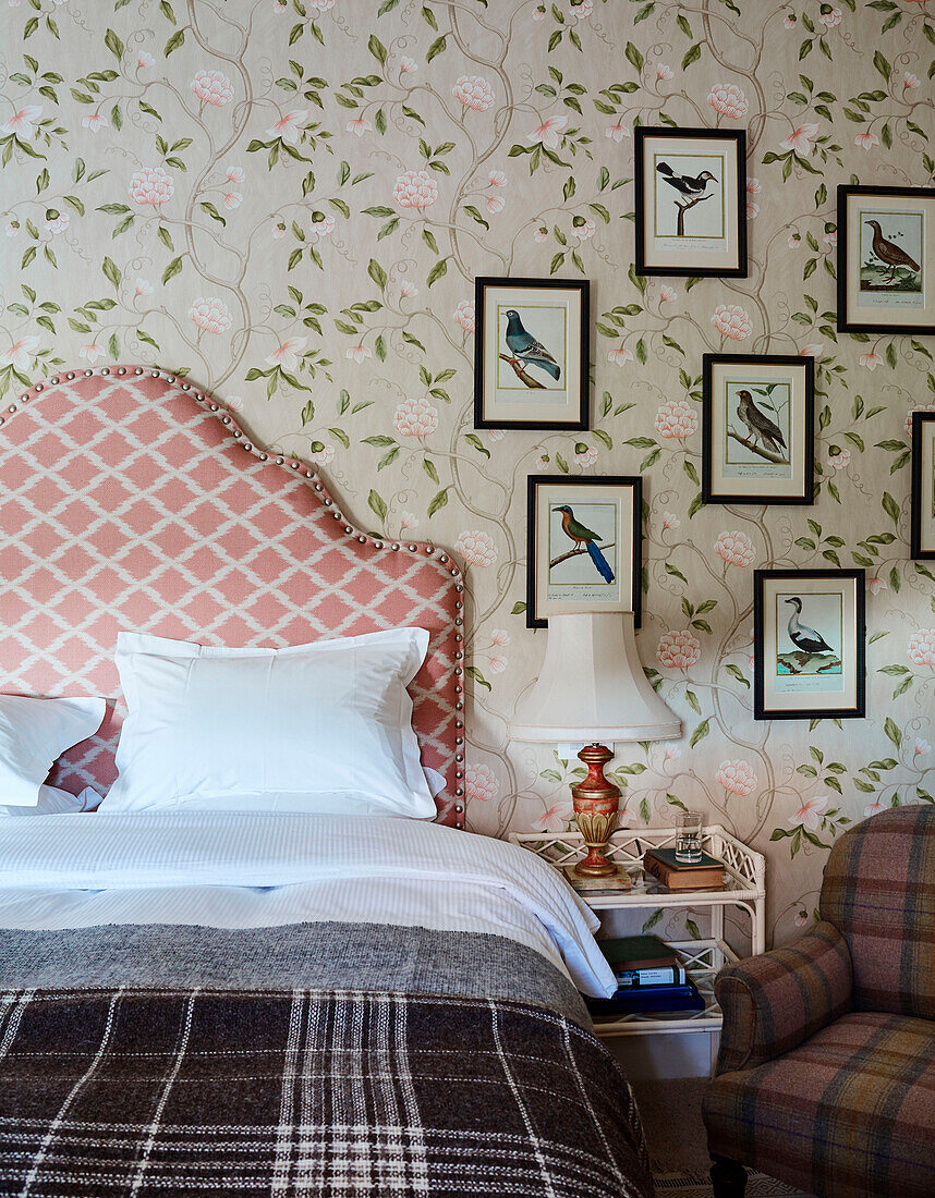 Floral wallpaper and framed prints with contrasting fabric designs and single bed in North Yorkshire farmhouse, UK