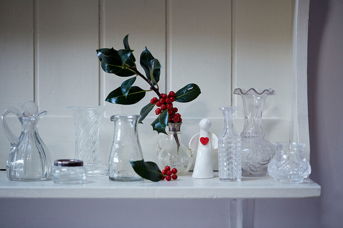 Holly leaves and berries with glassware on shelf