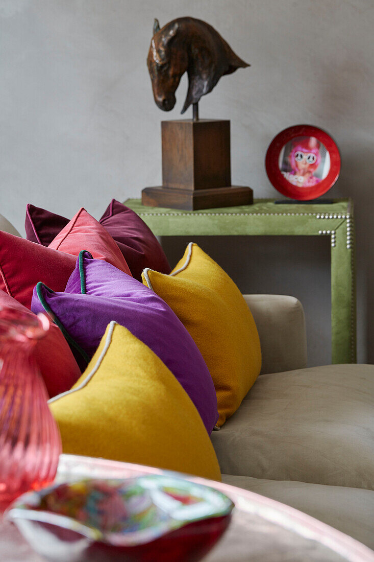 Bright cushions on sofa and equestrian bust in London apartment, UK