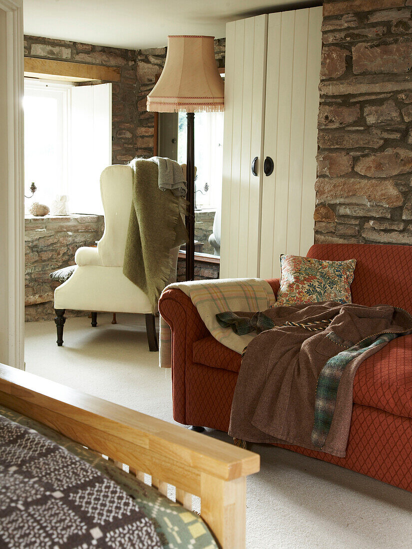 Schlafzimmer mit Sofa und Stühlen und freiliegenden Steinmauern