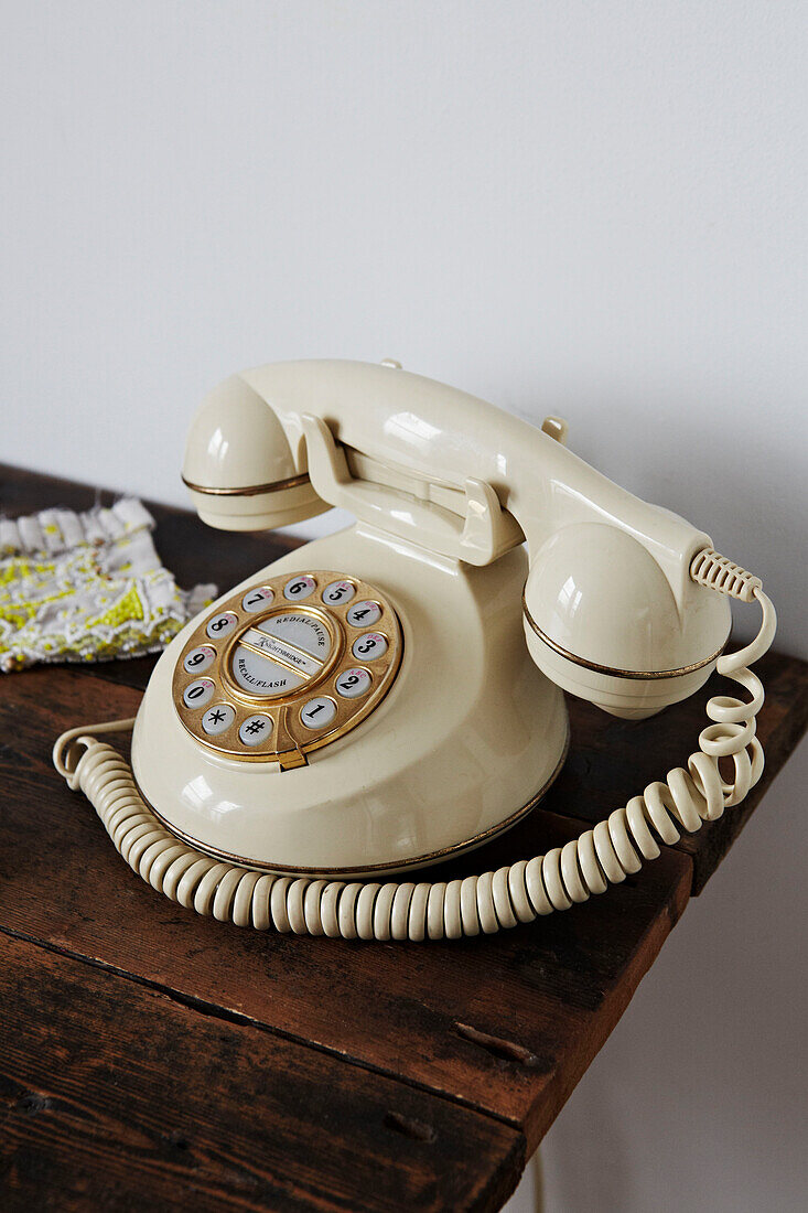 Telefon mit cremefarbener Wählscheibe auf einem hölzernen Beistelltisch in einem Einfamilienhaus in Colchester, Essex, England, UK