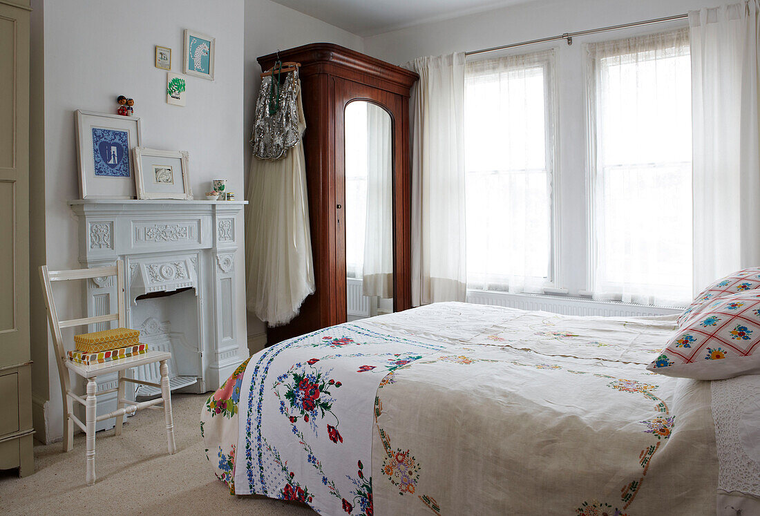 Bestickte Bettdecke und Gardinen mit verspiegeltem Kleiderschrank in einem Einfamilienhaus in Colchester, Essex, England, UK