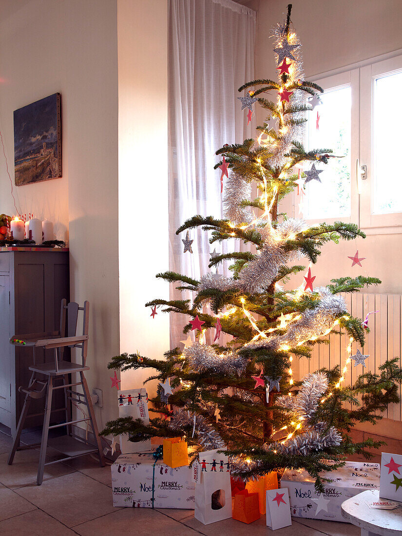 Weihnachtsbaum mit Lichtern und Geschenken in einem Familienhaus in Frankreich