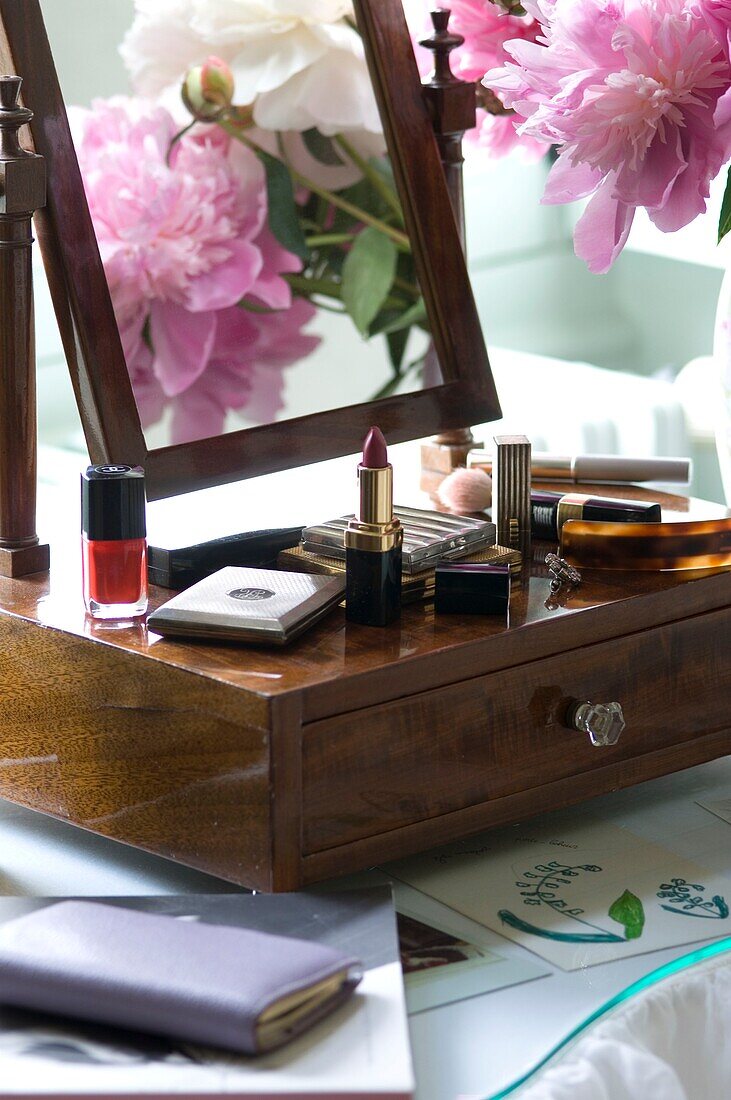 Cosmetics and peonies on vanity table