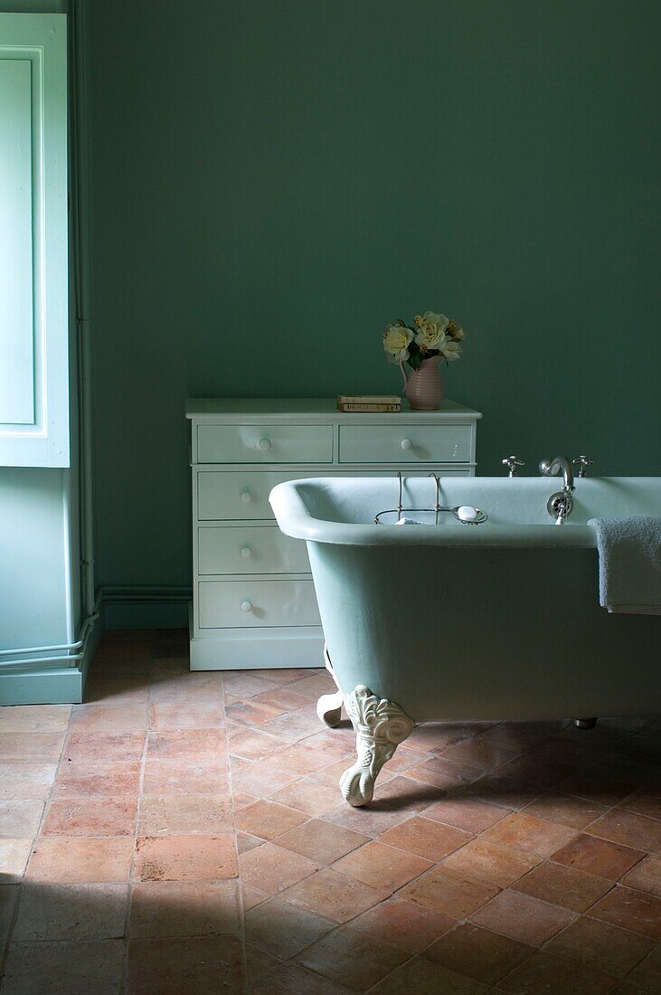 Bathtub and dresser in pastel green bathroom