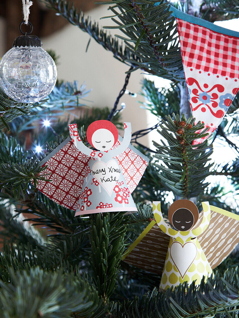 Papierengel und Glaskugel mit Wimpel im Weihnachtsbaum von einem Cottage in Herefordshire, England, UK