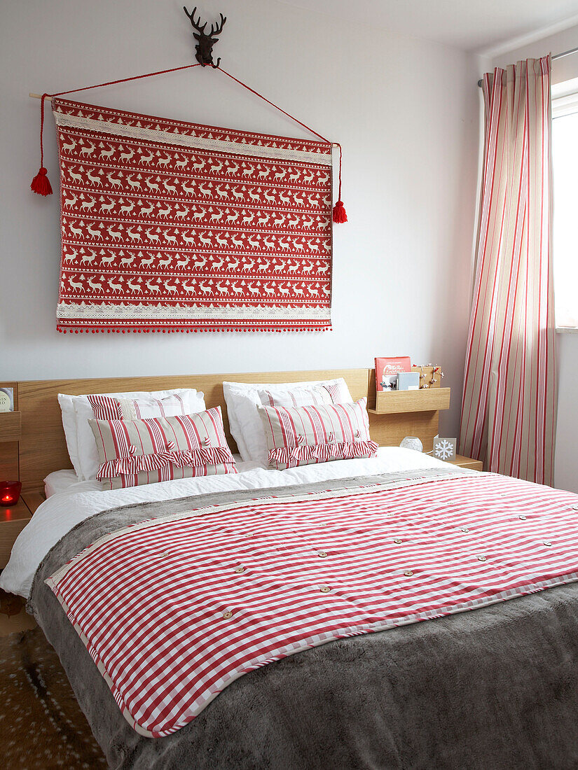 Red and white soft furnishings and wall hanging in bedroom of Polish home