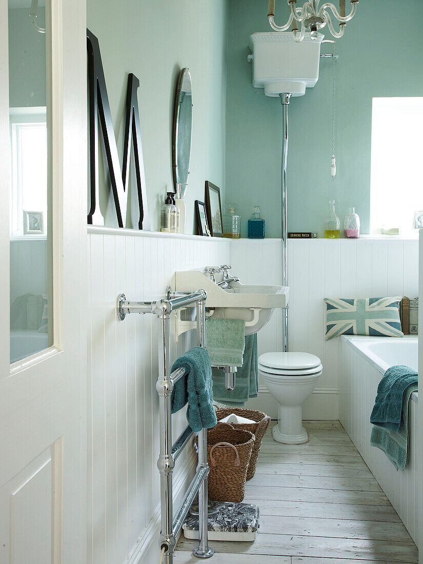 Badezimmer in Pastellgrün und Weiß mit wandmontiertem Spülkasten und übergroßem Buchstabem 'M' in einem Haus in Winchester, Hampshire, UK