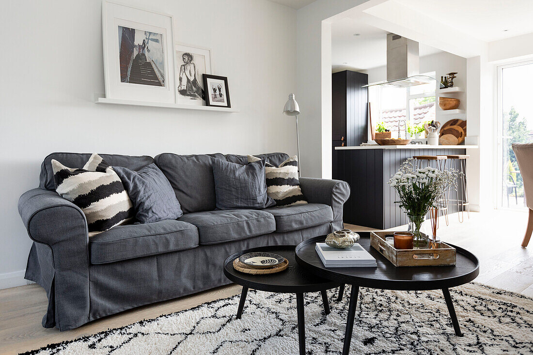 Schwarzer Couchtisch und graues Sofa mit gerahmten Kunstwerken im offenen Wohnzimmer in Reigate, Surrey, UK