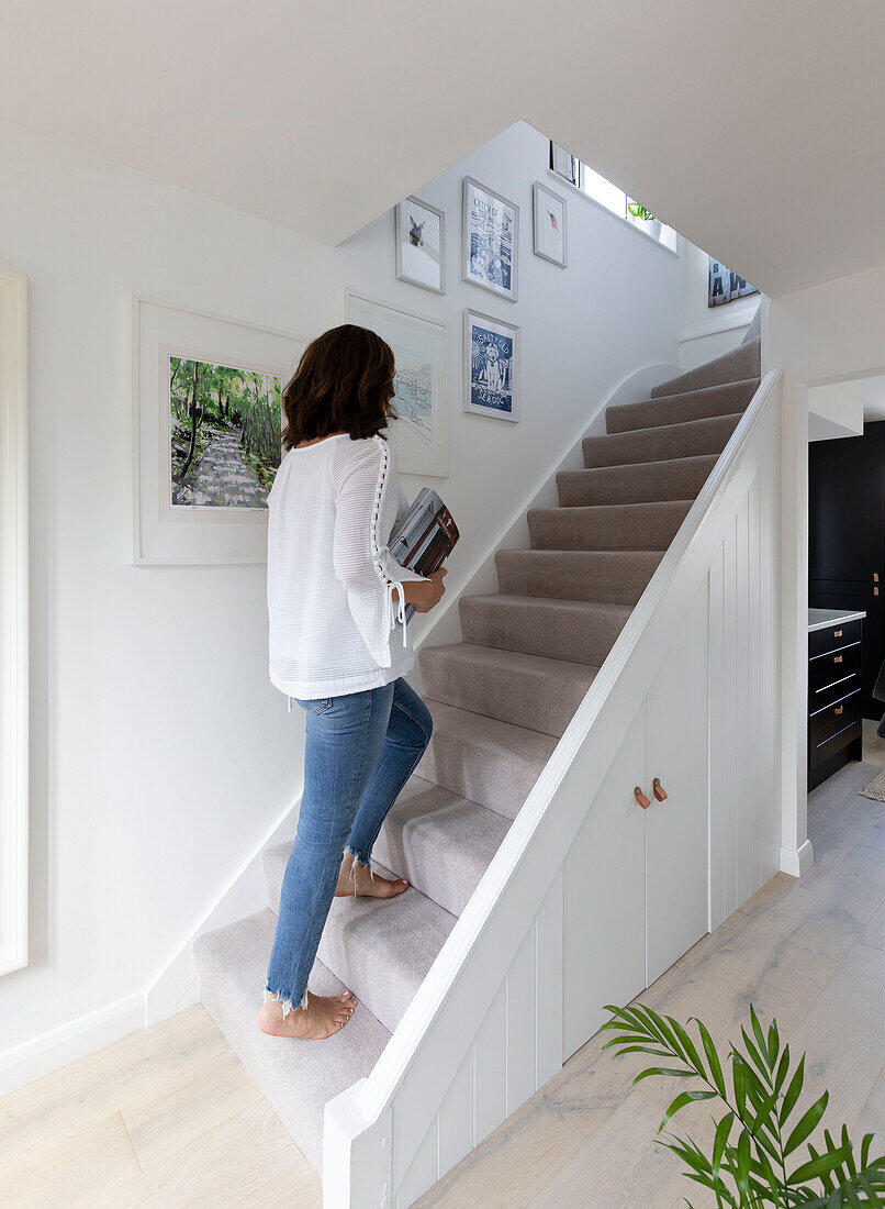 Woman climbing carpeted staircase in Reigate home, Surrey, UK