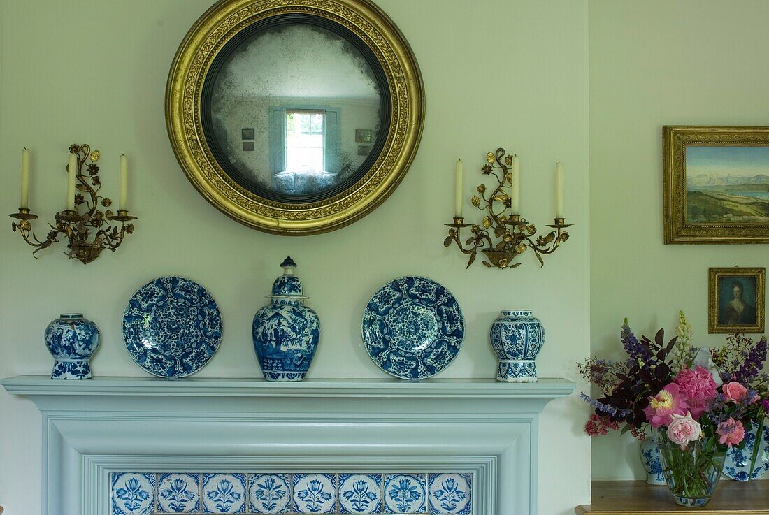 Kamin mit Kacheln im rustikalen Wohnzimmer mit dekorativen Porzellantellern und Vase