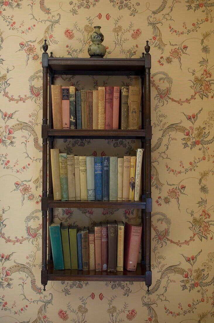 Bookshelf on wallpaper with floral pattern