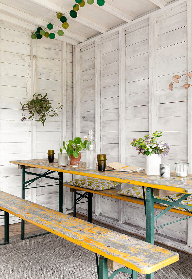Schnittblumen und Gläser auf Tisch mit Sitzbank im Atelierschuppen Guildford Surrey