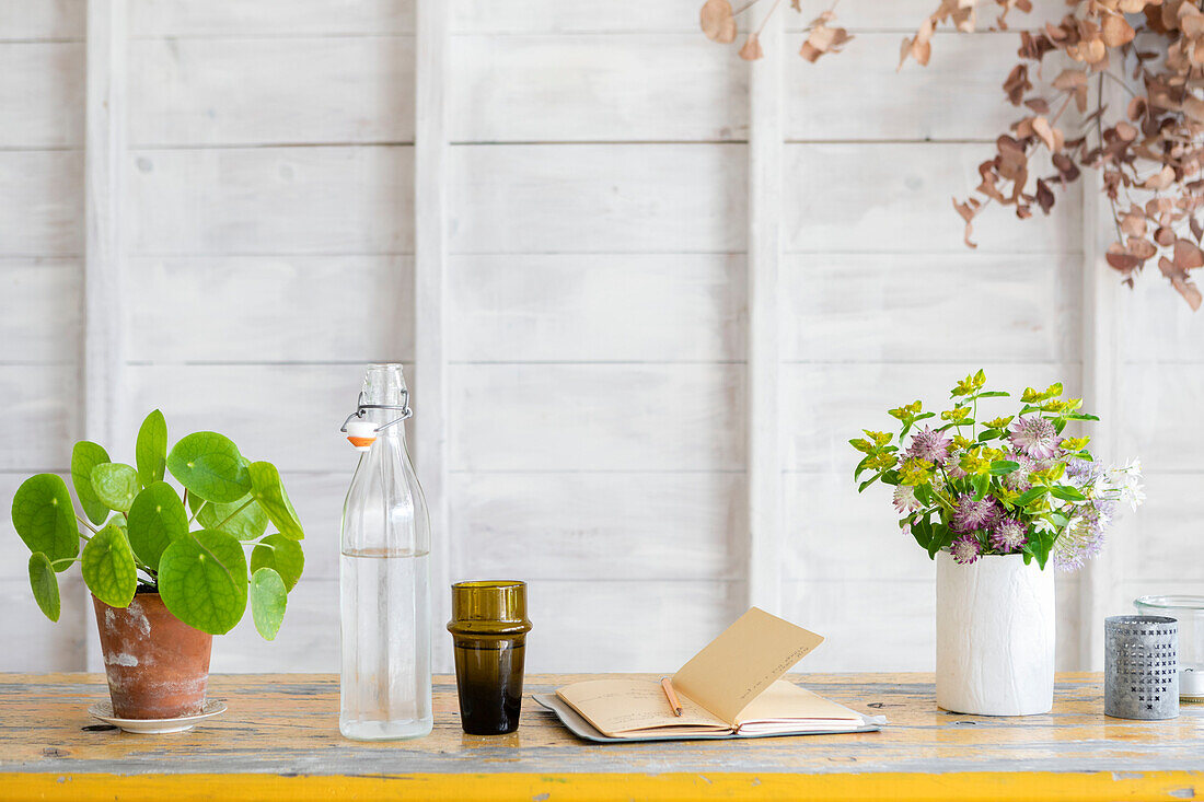 Zimmerpflanze und Blumen mit Notizbuch und Wasser im Atelierschuppen Guildford Surrey UK
