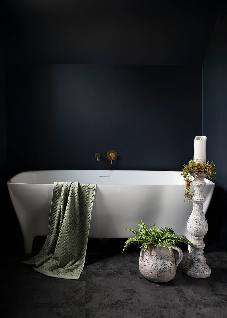 Vintage stoneware pieces make a bold statement in the bathroom and contrast with the modern bath against the dark walls