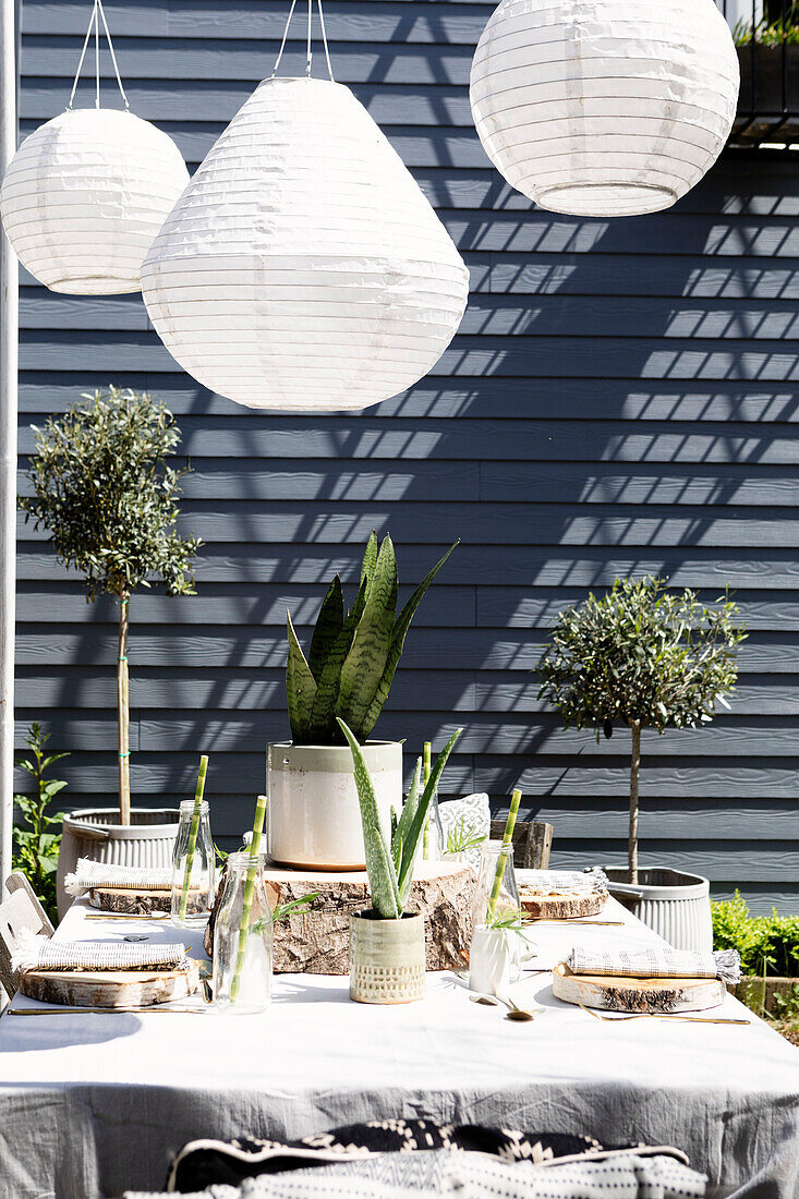 Solarlaternen über einem Tisch auf einer Terrasse mit sonnenbeschienener Holzverkleidung Colchester Essex UK